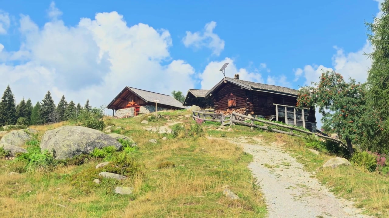 Fantastisk landskap som viser en alpehytte i San Giuliano-sjøområdet. En smal sti fører opp til trebygningen på en solrik dag