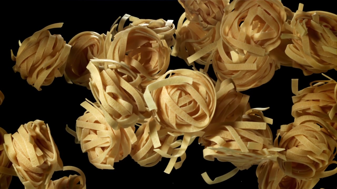 Nidi di pasta tagliatelle cruda che fluttuano su uno sfondo nero