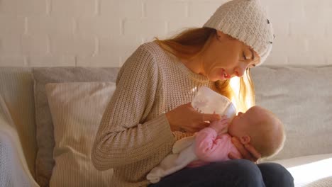 mother feeding milk to her baby boy in living room 4k