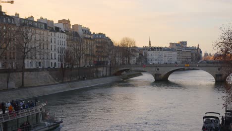 tourist boat on seine river by parisian bridge at sunset in paris, france