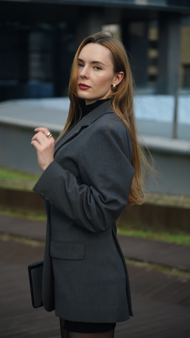 Caucasian seductive businesswoman looks at the camera then slowly turns into profile on a Seoul rooftop - camera moves closer in slow motion