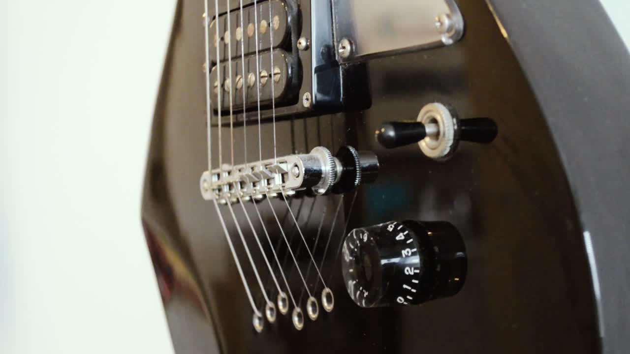 cuerpo de guitarra eléctrica negra colgado en una pared, de cerca