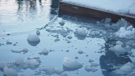 ice chunks floating on water next to a snowy wooden structure