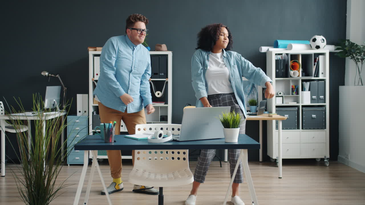 Two colleagues dancing in an office