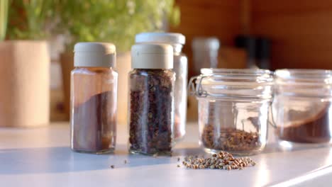 Storage-jars-of-seasonings-on-countertop-in-sunny-kitchen,-slow-motion