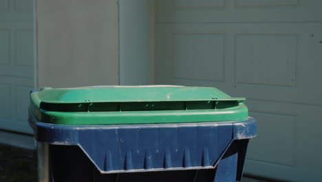 una bolsa de basura doméstica se tira a un basurero de plástico