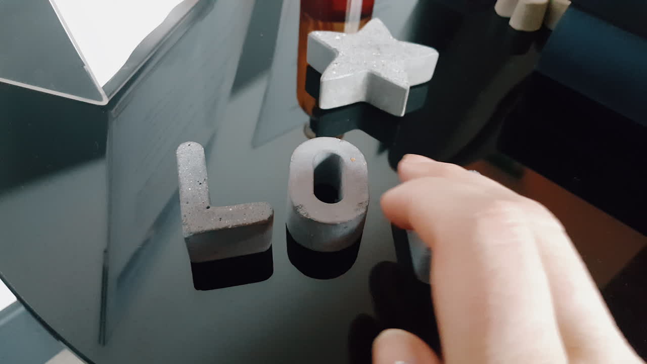 un primer plano de una mano haciendo la palabra amor de pequeñas letras de piedra
