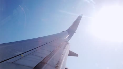 Blick-Aus-Dem-Flugzeug,-Blick-Durch-Die-Fenster-Auf-Die-Sonne-Und-Durch-Die-Wolken