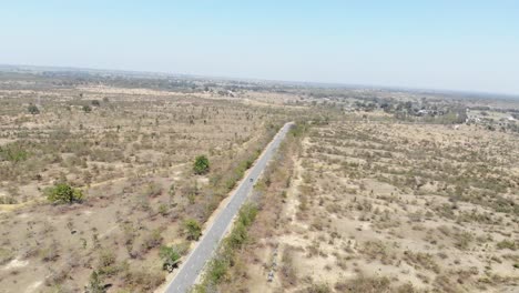 Aerial-shot-of-beautiful-vast-barren-land-near-Charu-village-in-Chatra,-Jharkhand,-India-with-a-road-passing-in-the-middle-and-a-bike-travelling