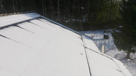 dron volando hacia atrás sobre paneles solares fangosos en el techo de una casa, noche de invierno