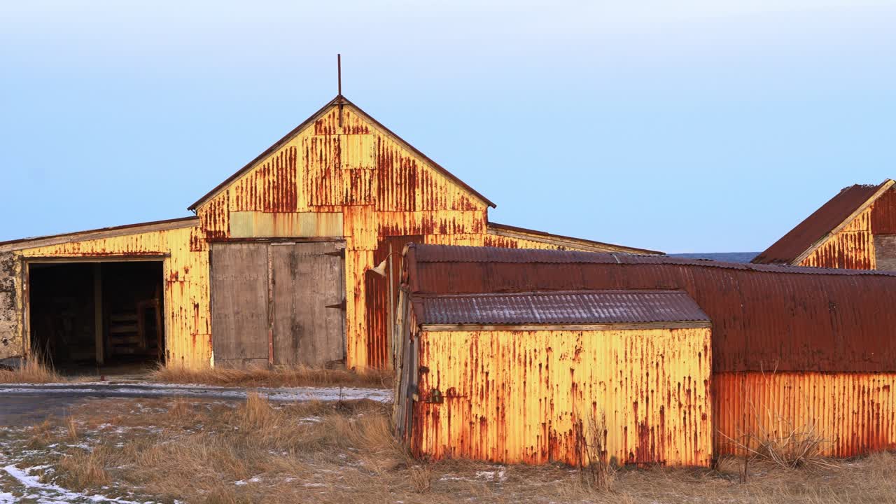 Desolate Icelandic barn in deep orange sunset, Nordic old architecture - handheld shot
