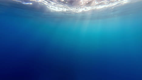 Underwater-shot,-upwards-to-the-surface-where-the-sun's-rays-penetrate