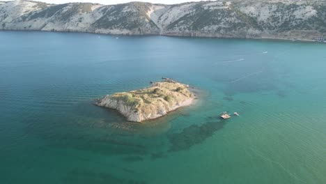 aerial of luxury sail boat yacht moored in open wide sea ocean water close to a little rocky islet exploring snorkelling and diving croatia