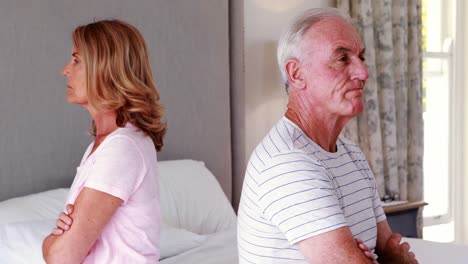pareja de ancianos molestos sentados de espaldas en la cama