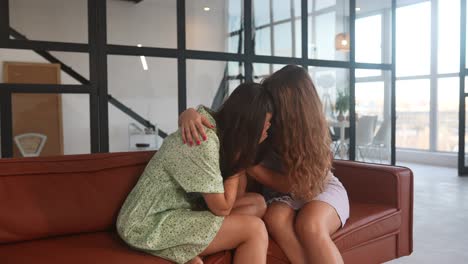 두 명의 여성이 소파에서 포옹하고 있습니다.