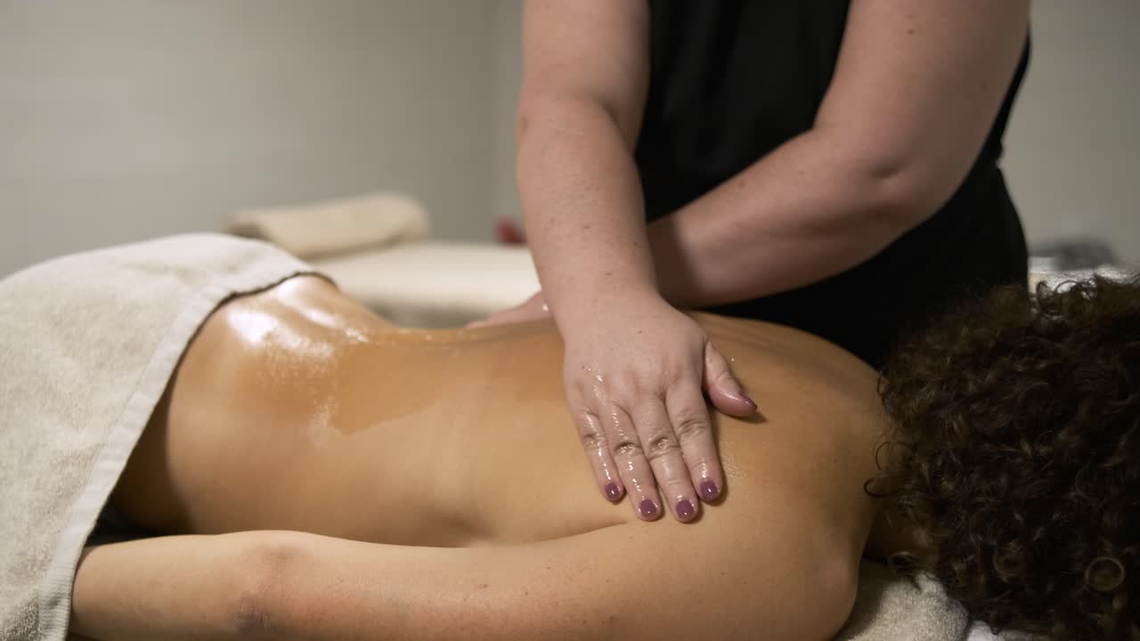 Masseuse performing back massage on client