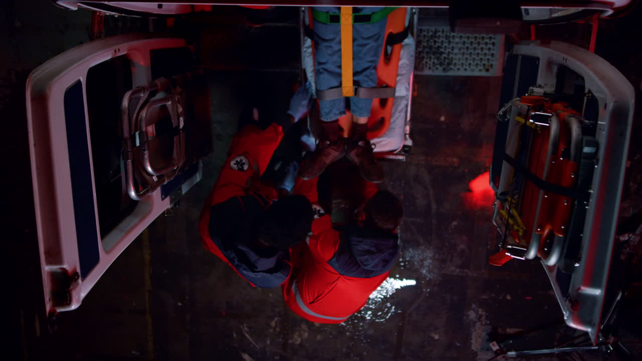 다민족 구급대원 들 이 응급차 에 탑승 한 부상자 를 옮기고 있다