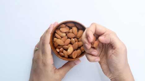 las manos de la mujer recogiendo almendras de un cuenco de madera