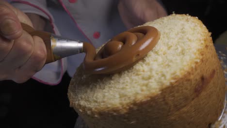 pastelero agregando caramelo de dulce de leche a un bizcocho