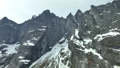 The-Troll-Wall-mountain-in-Romsdal-valley-Norway---Might-sharp-and-pointy-mountain-peaks-seen-from-rising-low-angle-aerial-looking-up