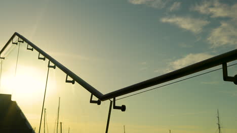 silhouetted geometric structure against sunlit sky with distant sailboat masts