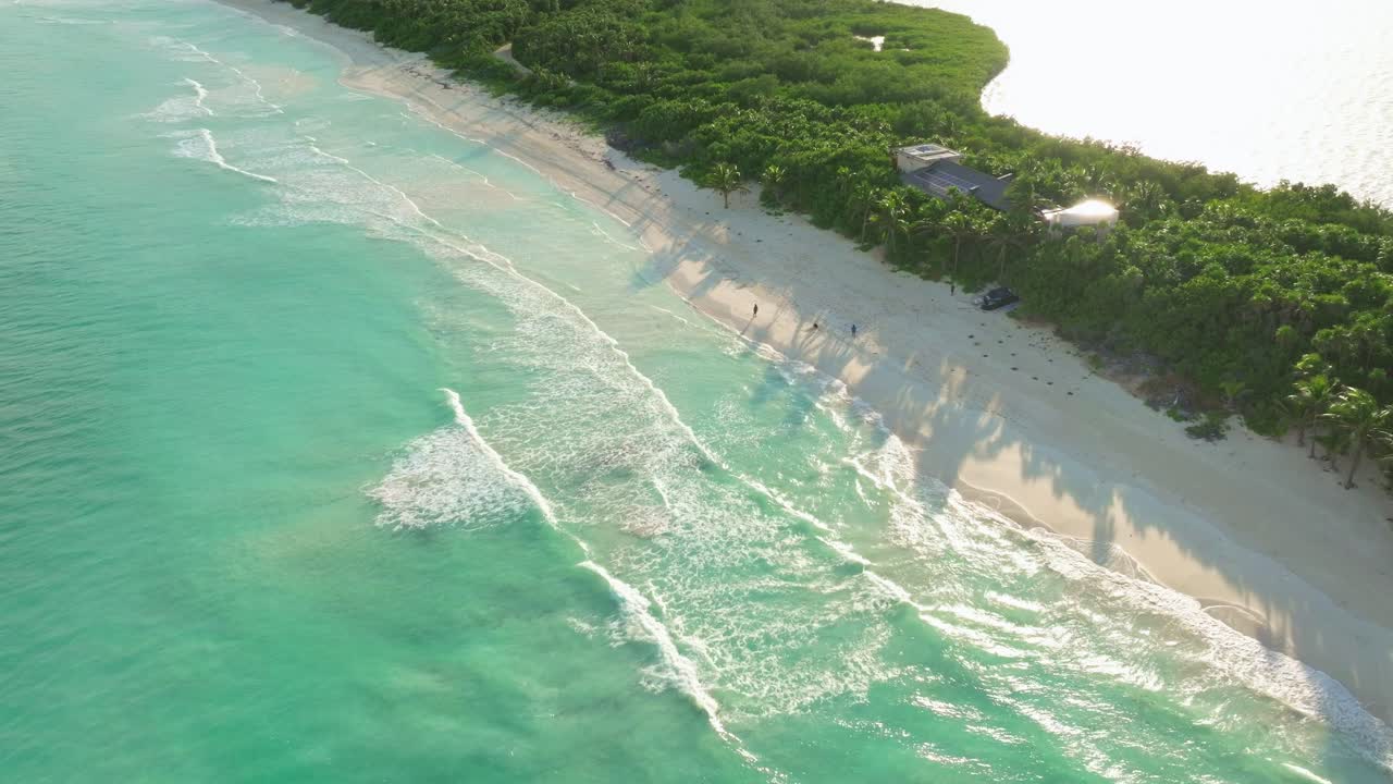 Aerial drone fly above blue waves reaching Tulum Mexico shoreline in a wild reservoir natural area