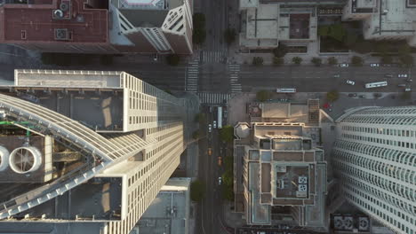 Passing-by-Huge-Office-Building-Skyscraper-Rooftops-in-Downtown-Los-Angeles,-Aerial-Birds-Eye-Overhead-Top-Down-View-of-City-Street-with-little-Car-traffic