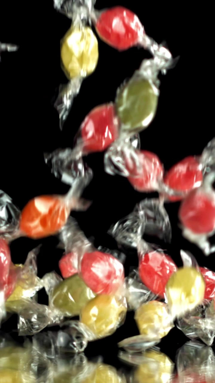 Doces coloridos embalados caindo em câmera lenta.