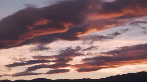 drone filming of a spectacular sky at sunset in a valley with yellow-orange and reddish tones mixed with very striking grays with a blue and cream-colored background all reflected in the clouds