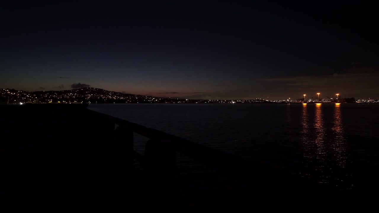 Kaliforniya, San Pedro'da gece Cabrillo Plajı iskelesinin, uzakta Los Angeles Limanı ve Palos Verdes ile birlikte gimbal ile yakın çekim kaydırma görüntüsü. 4K.