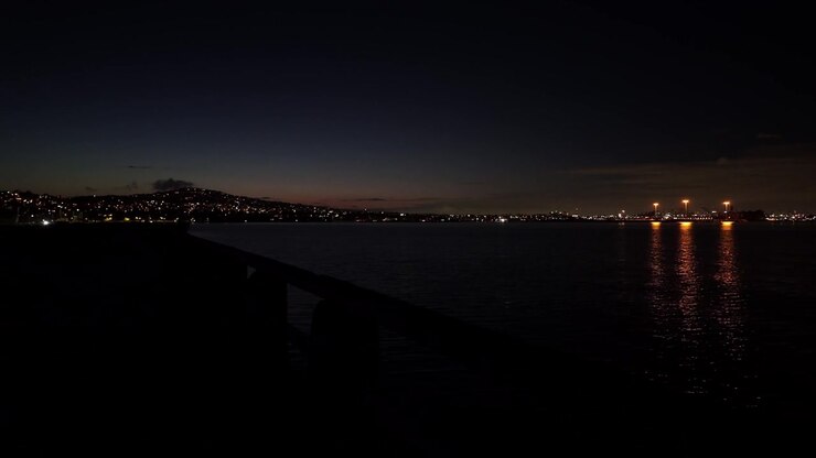 Primo piano panoramico con gimbal del molo di Cabrillo Beach con il Porto di Los Angeles e Palos Verdes in lontananza di notte a San Pedro, California. 4K.