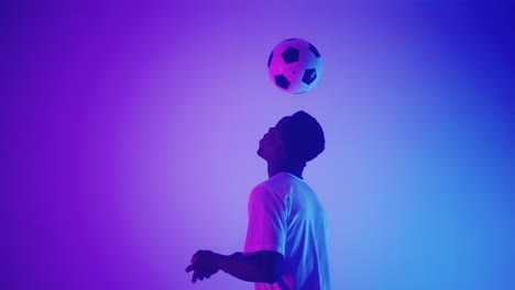 futbolista africano está pateando la pelota por cabezas en el estudio haciendo keppie uppie habilidad para el jugador de campo