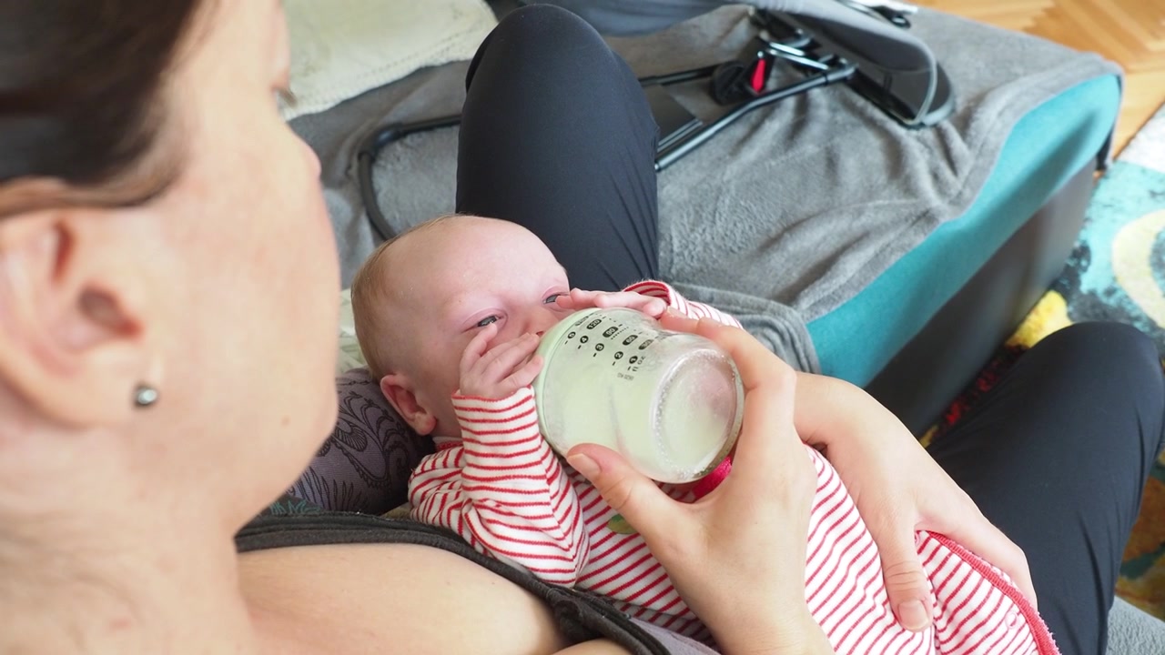 Madre che nutre il bambino con il biberon di latte. Vista dall'alto