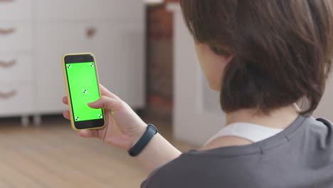 el entrenamiento en línea de la joven. pantalla verde y marcas en su teléfono.