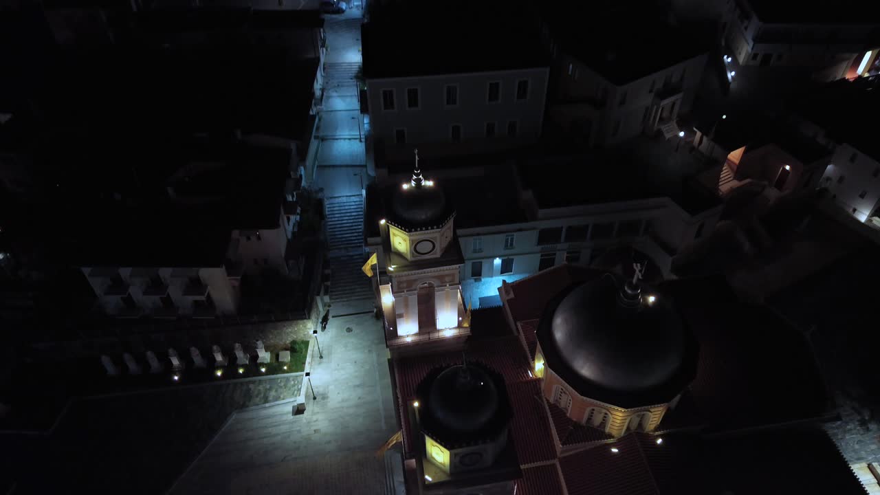 Aerial, bird's eye top view of famous Christian orthodox Ypapanti church, located at historical center of Kalamata, night footage, push in, tilt down 4K