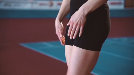 deportista rubia calentando y estirando las piernas en una instalación deportiva cubierta