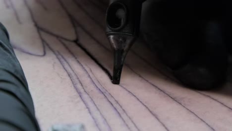 close up of needle tattoo machine injecting a black ink into the skin and drawing line.