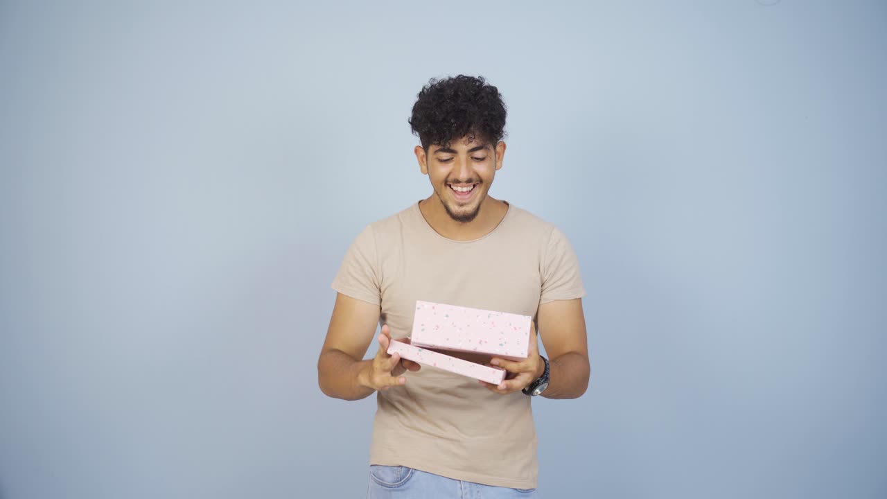 행복하고 즐거운 남자가 선물 패키지를 열고 있습니다.