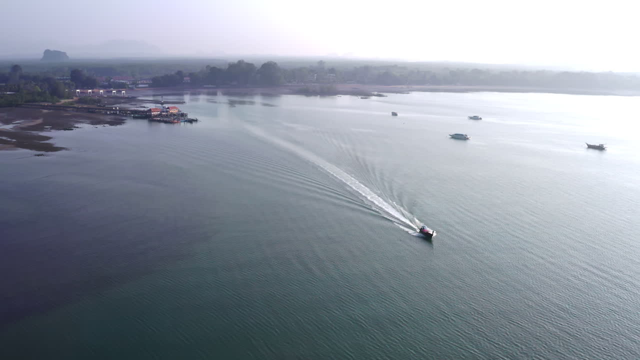 лодка с длинным хвостом быстро плывет с туманного побережья таиланда в открытое море