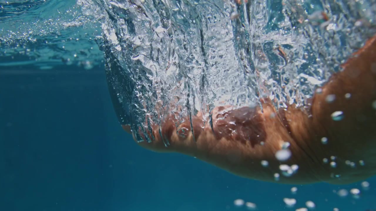 Il movimento del corpo sommerso genera scie di bolle turbolente sotto l'acqua tropicale dell'Atlantico vicino a Preá, Ceará, Brasile, ripresa d'azione subacquea in super slow motion con distorsione della superficie