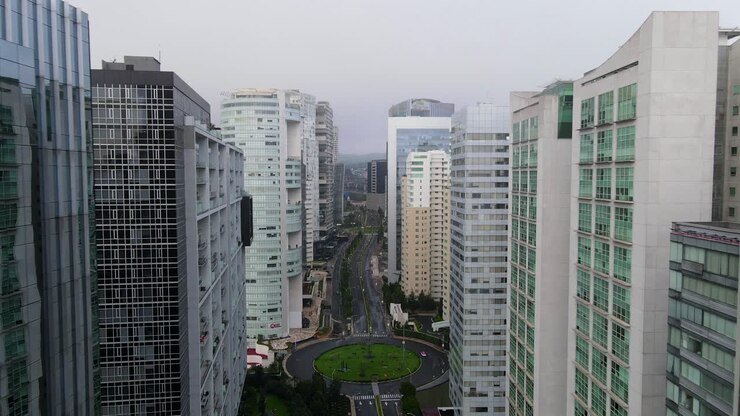Gliding between Santa Fe high buildings - skyscrapers in Mexico city above nearly empty roads during Covid-19 pandemic and cloudy sky