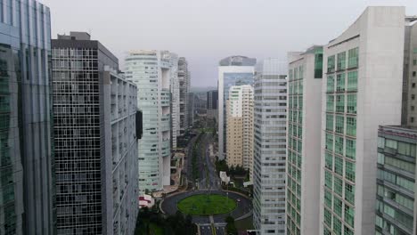 Gliding-between-Santa-Fe-high-buildings---skyscrapers-in-Mexico-city-above-nearly-empty-roads-during-Covid-19-pandemic-and-cloudy-sky