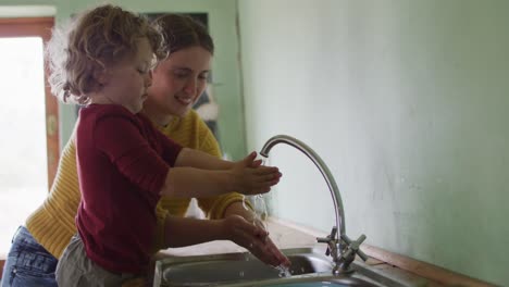Glückliche-Kaukasische-Mutter-Und-Sohn-Waschen-Sich-In-Der-Küche-Die-Hände