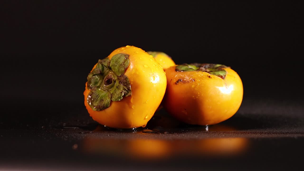 caqui con gotas de agua sobre un fondo oscuro
