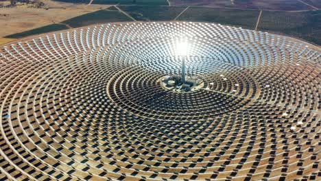 solar panels in a large thermal circular power plant with the reflection of the sunlight in the panels. renewable and pollution-free energy in a solar farm in spain- aerial view with a drone - environmental concept