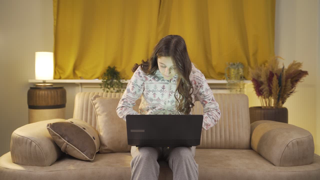 una joven que se centra en la computadora tiene una expresión seria. en casa por la noche.