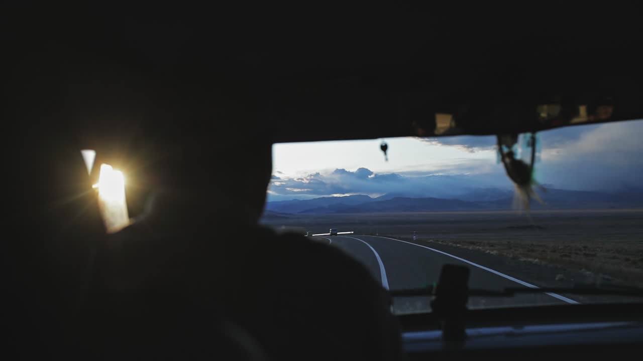 몽골의 알타이 산맥에서 해가 지는 도로에서 차량의 앞 창문에서 볼 수 있는 모습