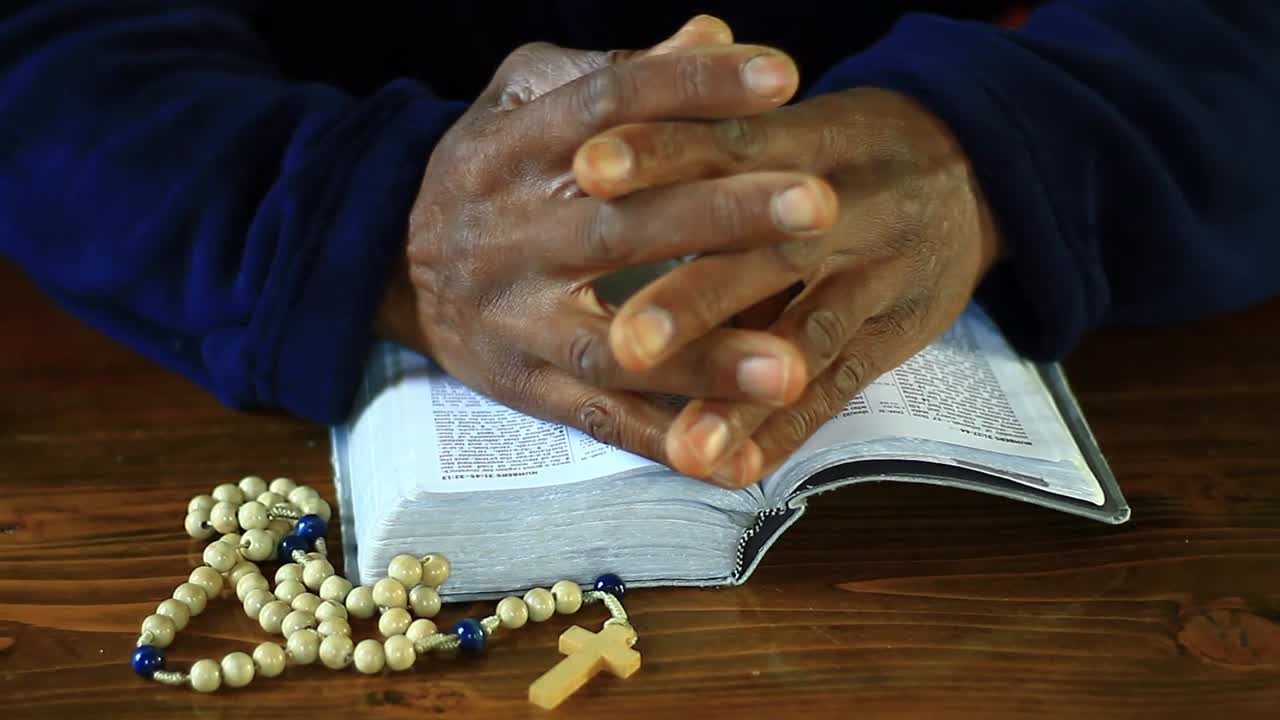 Beten zu Gott mit zusammengelegten Händen auf einer Bibel, mit Menschen und weißem Hintergrund, Stock-Video.