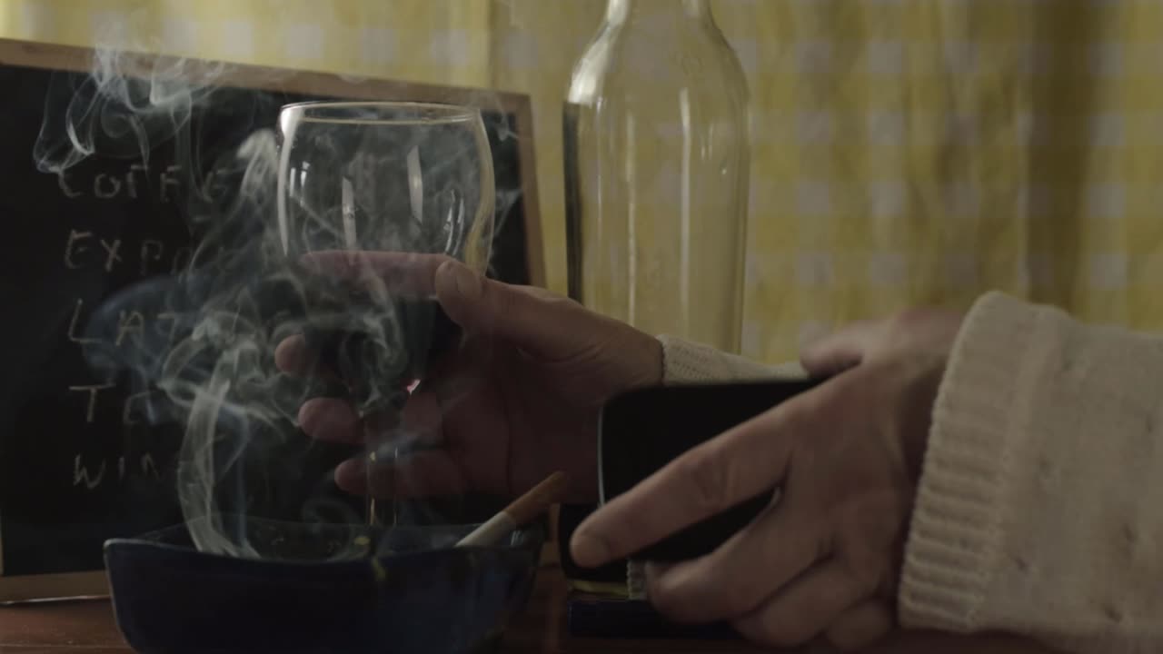 manos encendiendo un cigarrillo y revisando el teléfono celular en un bar plano medio