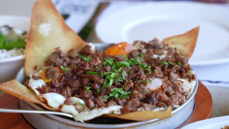 savory skillet with spiced meat, fried eggs, crispy bread, and herbs—ideal for food content, middle eastern cuisine, brunch, or restaurant promo